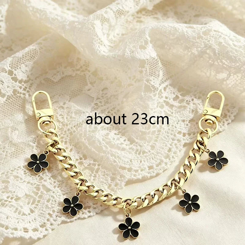 Gold chain necklace with black bag flower charms on a white lace fabric background