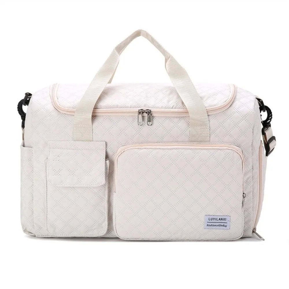 A cream-colored quilted travel duffle bag with light beige handles and a zippered pocket.
