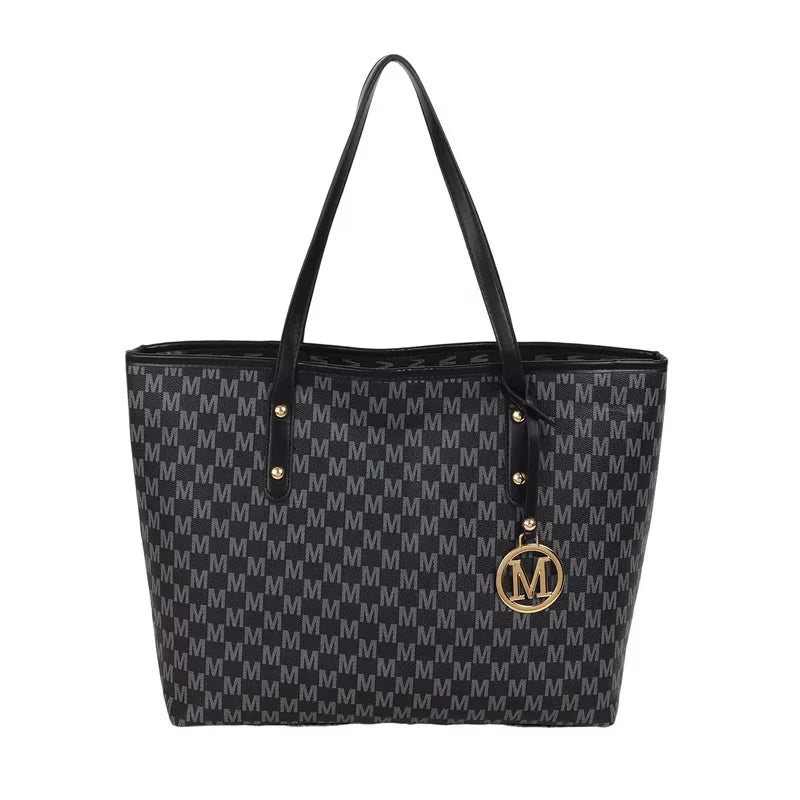 A black faux leather tote bag with a monogram print and gold hardware.