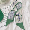 Un foulard pour les cheveux en soie vert et blanc, à côté d'un document sur l'Espagne.