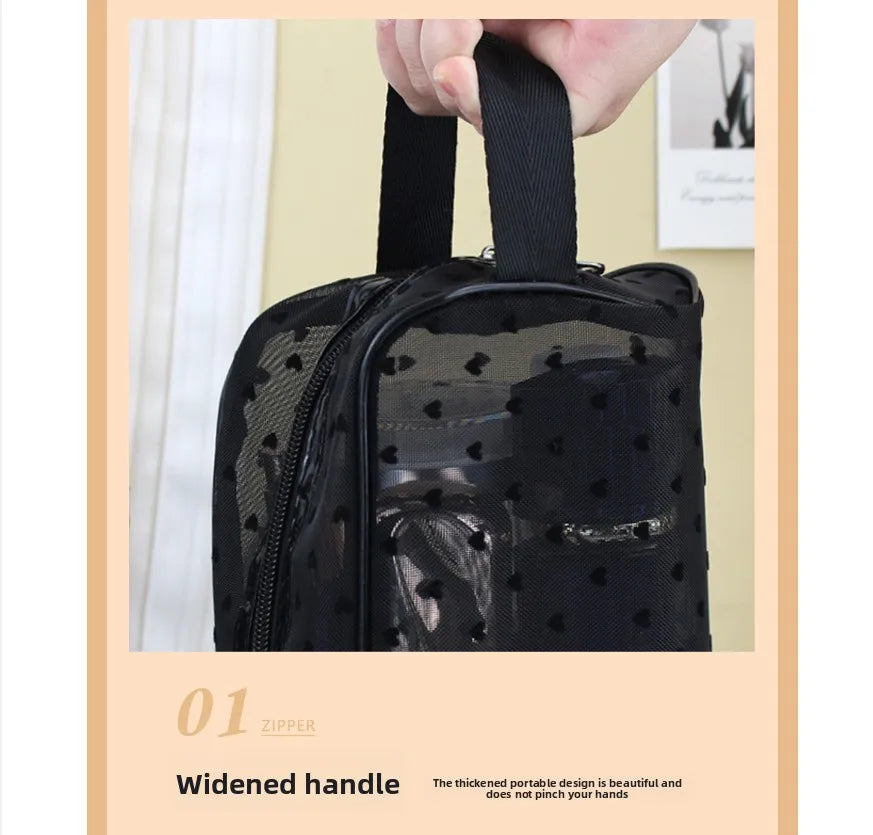 A black mesh transparent makeup storage bag with a widened handle is being held by a hand.
