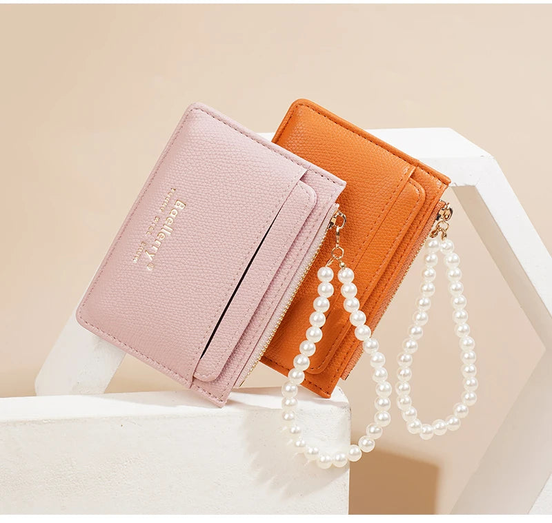 Multifarbige, lachsrosa und orangefarbene Kartenwallet mit Perlenketten auf weißem Untergrund.