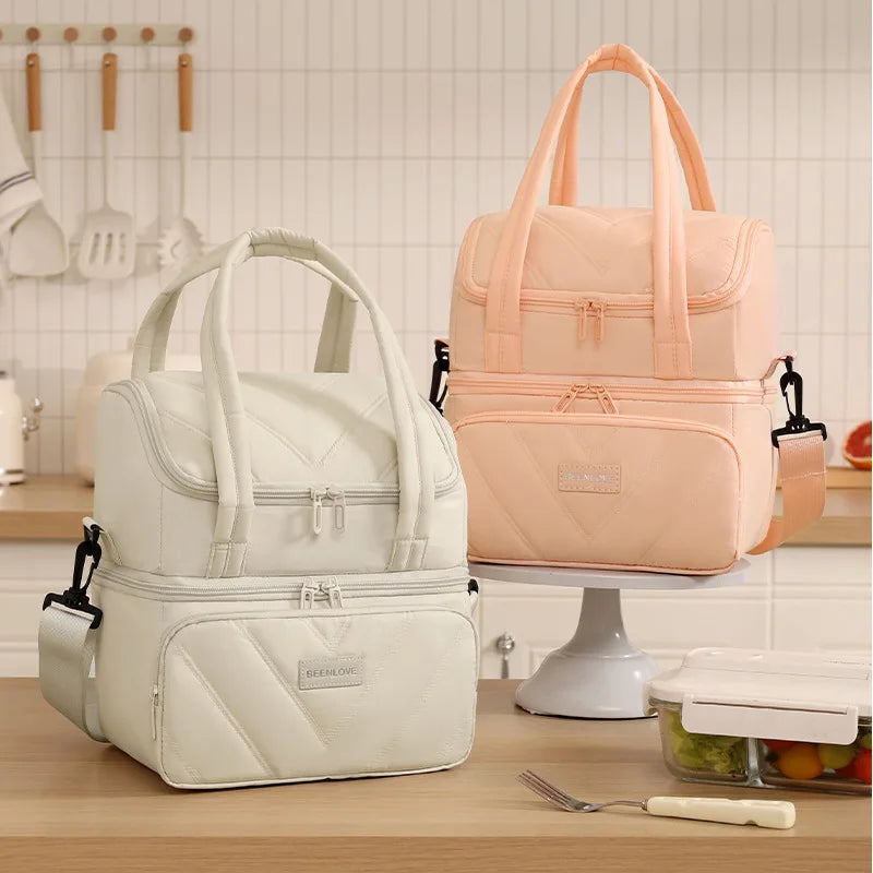 A pink and white double-layer insulated lunch bag is displayed on a stand.