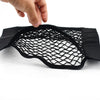 A hand is holding a black net bag designed for universal car trunk storage organization.