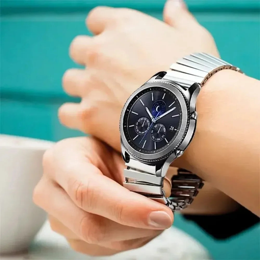 A person is wearing a silver stainless steel watch with a dark face and blue accents on a wrist.
