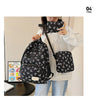 A woman holds a black nylon travel backpack featuring a white bow print on it.