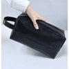 A hand is holding a black portable PU leather cosmetic organizer bag.