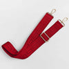A red fabric strap with a maze pattern and gold-toned hardware, shown diagonally.