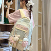 A young woman is wearing a light pink shirt and gray pants while carrying a pastel green Kawaii Harajuku backpack.