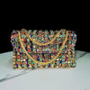 A sparkling rhinestone evening clutch bag featuring a gold diamond chain detail.