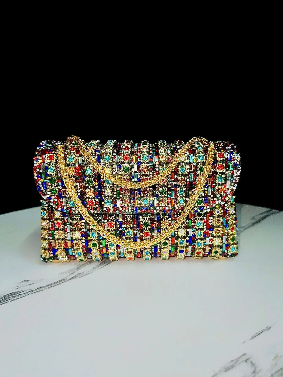 A sparkling rhinestone evening clutch bag featuring a gold diamond chain detail.