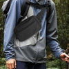 A black tactical concealed carry fanny pack is worn on a person's chest under a gray jacket.