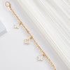 A delicate gold chain with small floral charms is displayed against a white background.