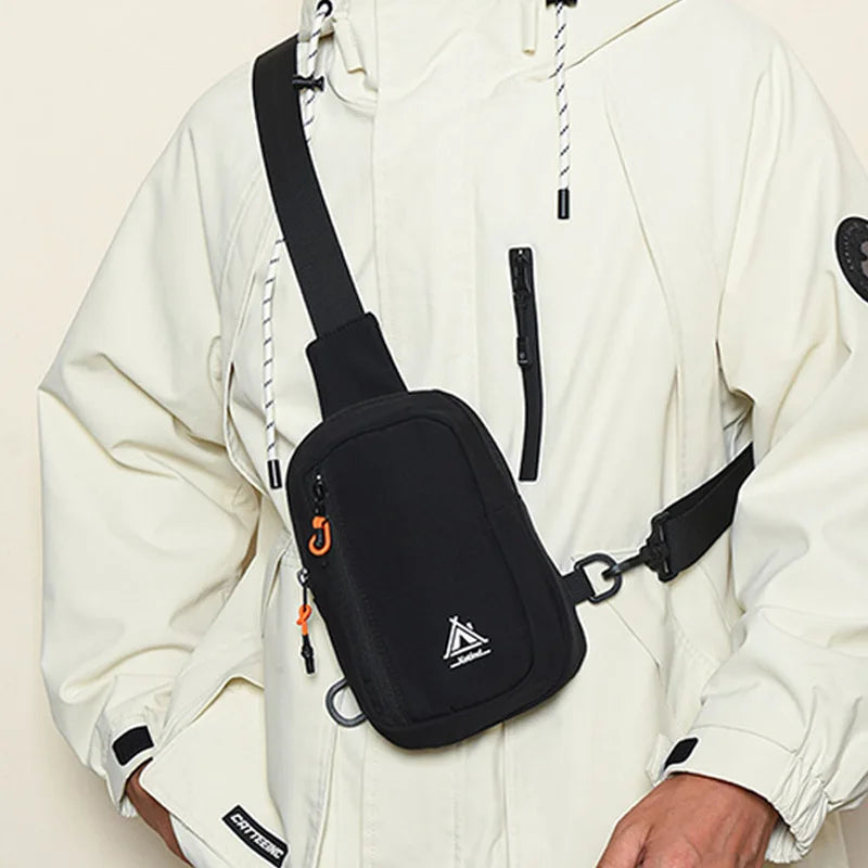 A person is wearing a black nylon sling crossbody bag attached to a light-colored jacket.