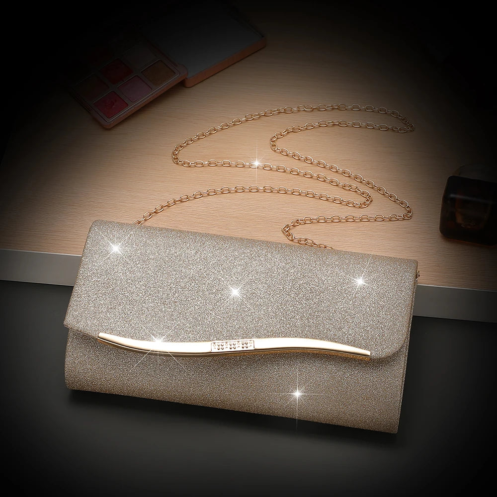 A gold sequined envelope clutch with a detachable chain rests on a wooden surface.
