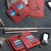 A red floral genuine leather card wallet with multiple slots and a metal clasp resting on a dark gray fabric.