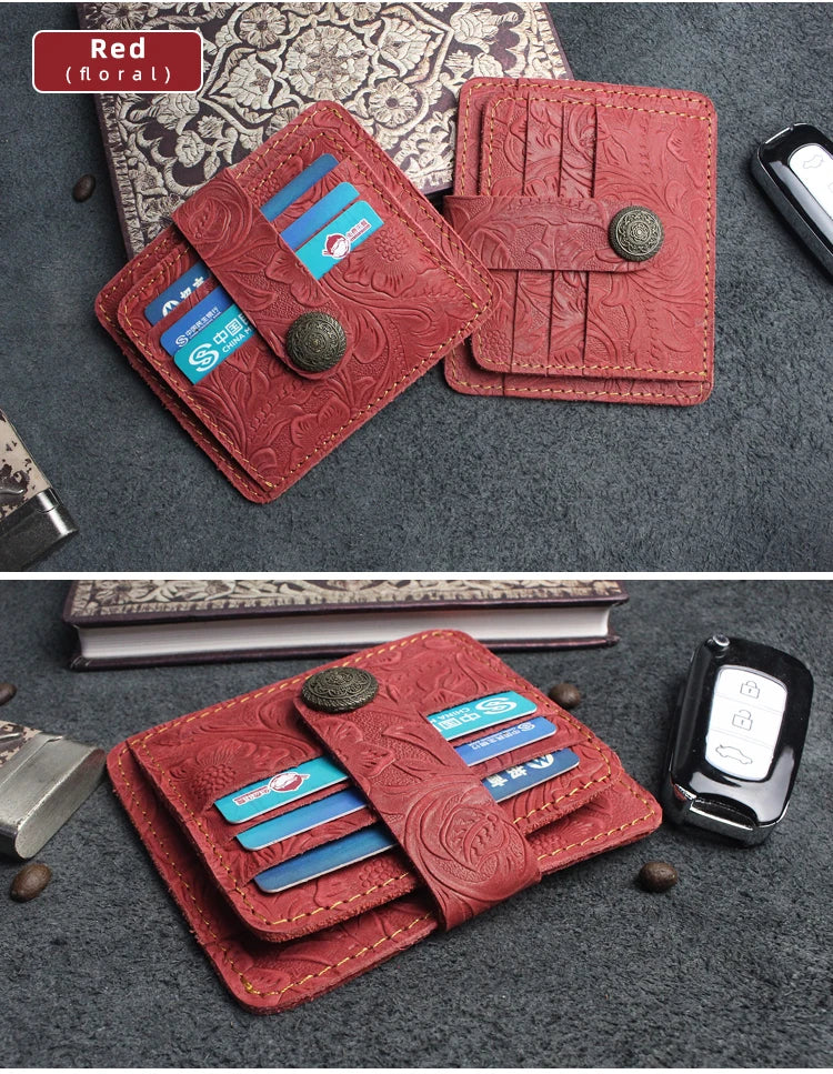 A red floral genuine leather card wallet with multiple slots and a metal clasp resting on a dark gray fabric.