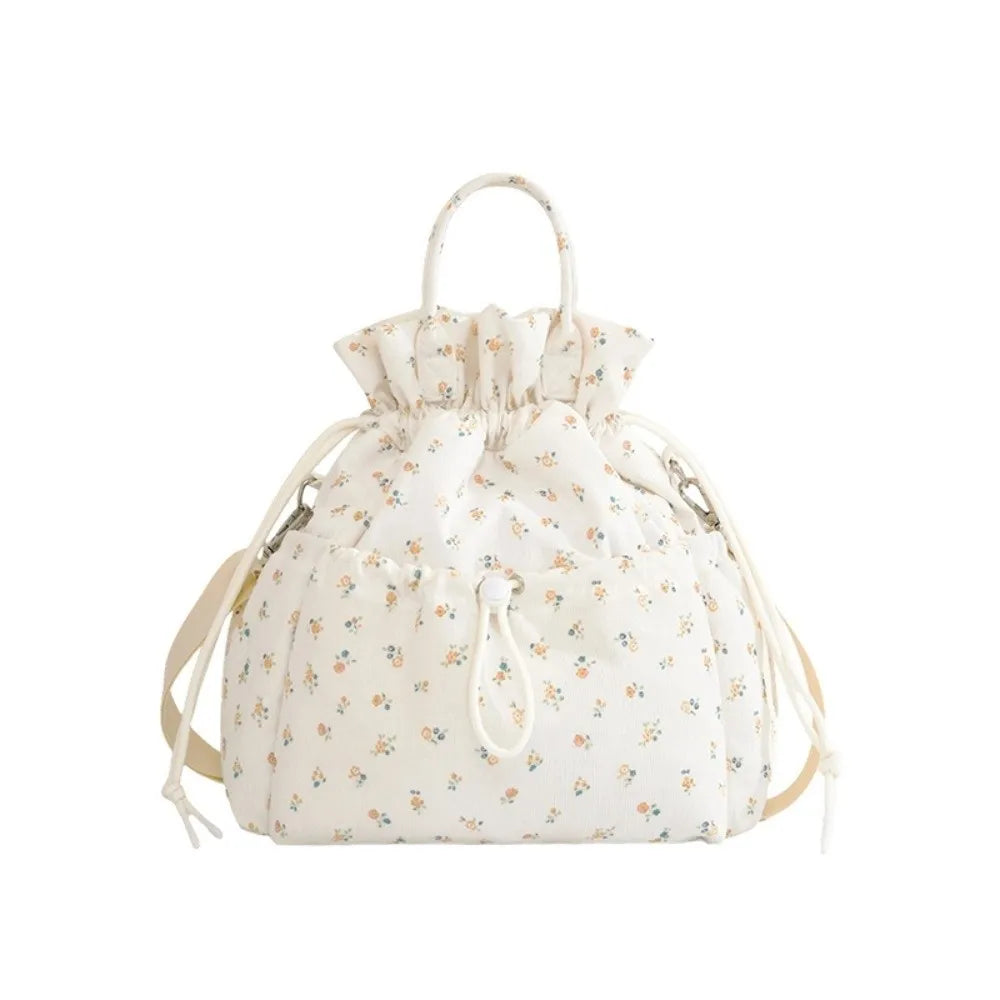 A cream-colored insulated waterproof lunch bag with a drawstring closure and a floral pattern.
