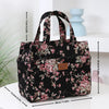 A black cloth tote bag with a pink floral pattern is displayed on a white surface.