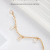 A delicate gold chain with floral charms draped across a white background.