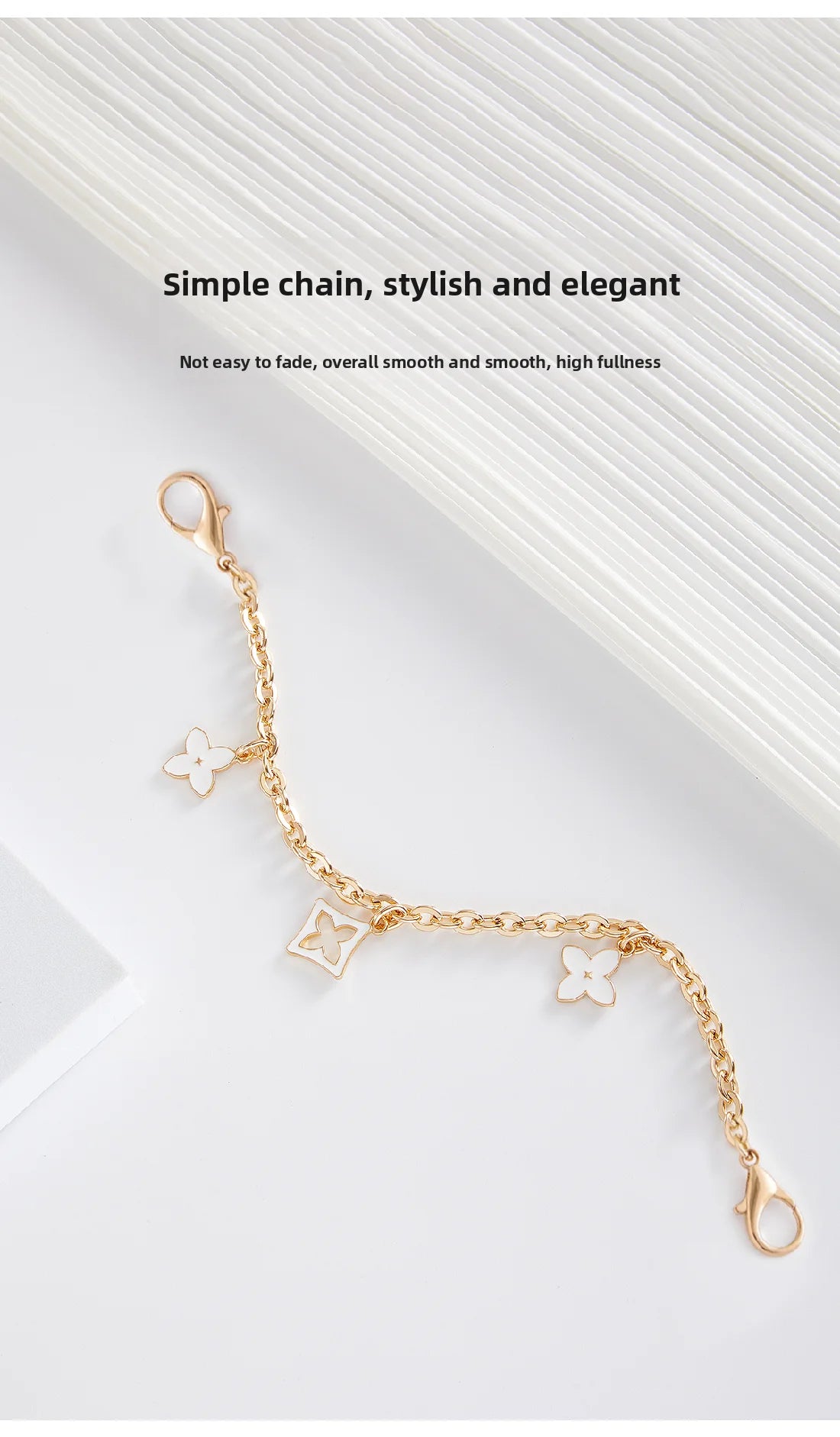 A delicate gold chain with floral charms draped across a white background.