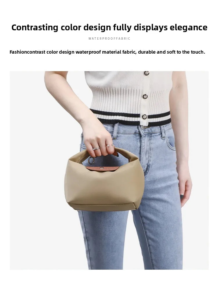 A person is holding a beige nylon dumpling crossbody shoulder bag against a light background.