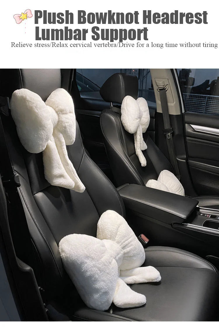 A white plush bowknot headrest pillow and lumbar support placed on a black car seat.