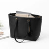 Bolso tote de cuero sintético negro con un teléfono claro y un dije de cadena dorada