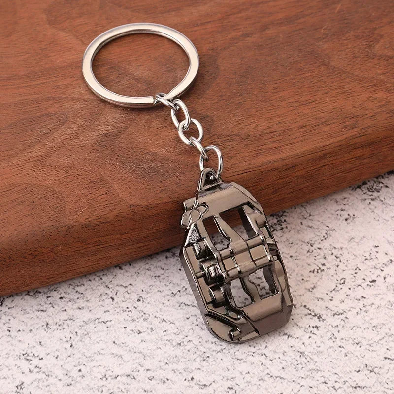 مفتاح سلسلة (كيشِن) بصندوق تروس فضي بحلقة دائرية، موضوع على سطح خشبي داكن.