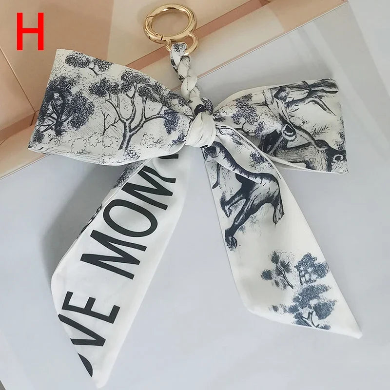 Lazo de cinta de seda blanca con silueta en blanco y negro de árboles y animales.