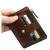 A brown leather card holder wallet is being held by a hand, showing the interior slots for cards.