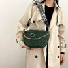 A beige trench coat features a dark green quilted woven pattern waist bag with a black and white patterned strap.