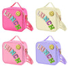 Pink, yellow, and purple insulated lunch bags with decorative patches and adjustable straps.