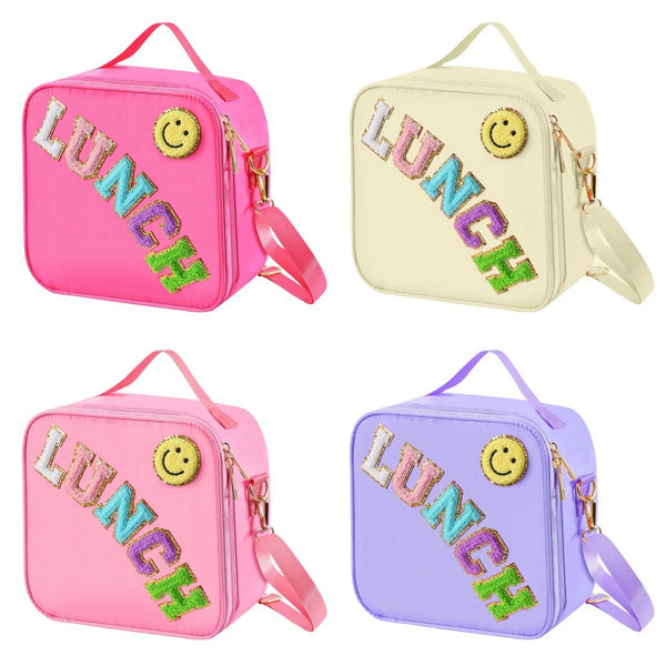 Pink, yellow, and purple insulated lunch bags with decorative patches and adjustable straps.
