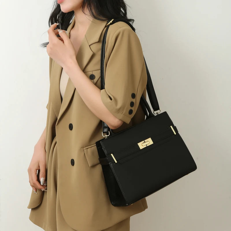 A woman wearing a beige trench coat carrying a black leather luxury handbag.