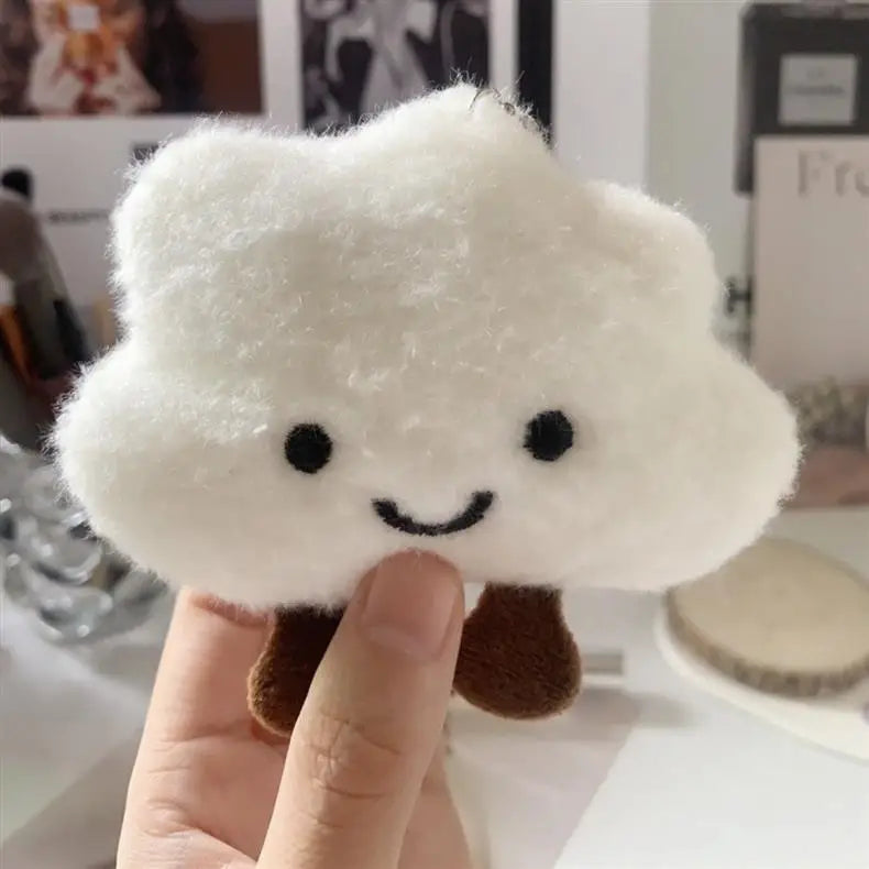 A white fluffy cloud shaped plush toy with black eyes and a brown stem is being held by a hand.