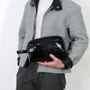 A person holds a black crocodile-textured PU leather clutch bag against a gray jacket.