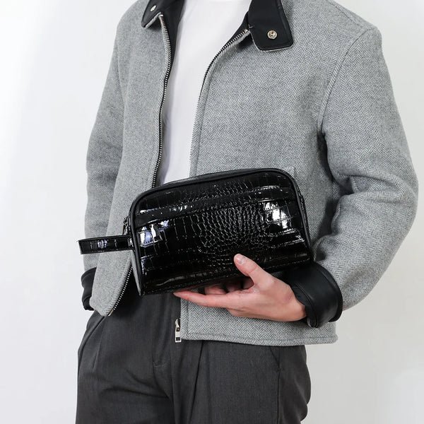 A person holds a black crocodile-textured PU leather clutch bag against a gray jacket.