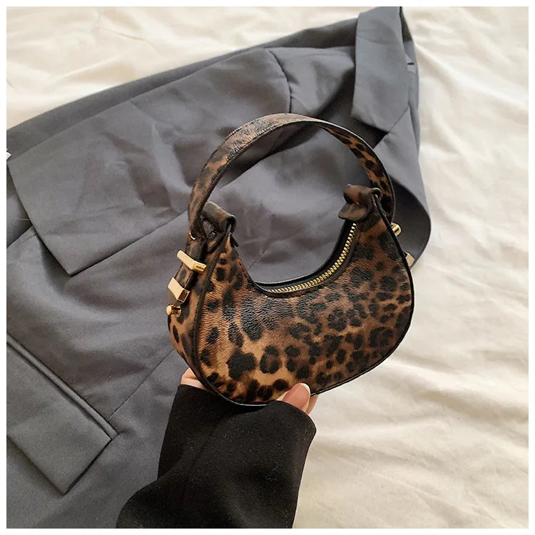 A brown leopard print PU leather mini tote handbag is shown against a gray blazer on a light background.