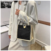 A woman holds a light beige blazer and a black and cream floral linen tote bag.