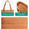 Gros plan d'un sac fourre-tout matelassé beige avec poignées rembourrées, fermeture éclair supérieure et tissu résistant à l'