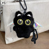 Colgante llavero de peluche de gato negro con grandes ojos amarillos, exhibido contra una bolsa de color claro.