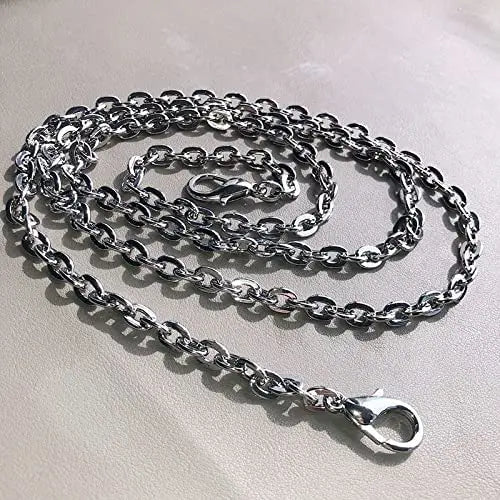 A silver stainless steel diamond-cut curb chain bag strap coiled on a light surface.