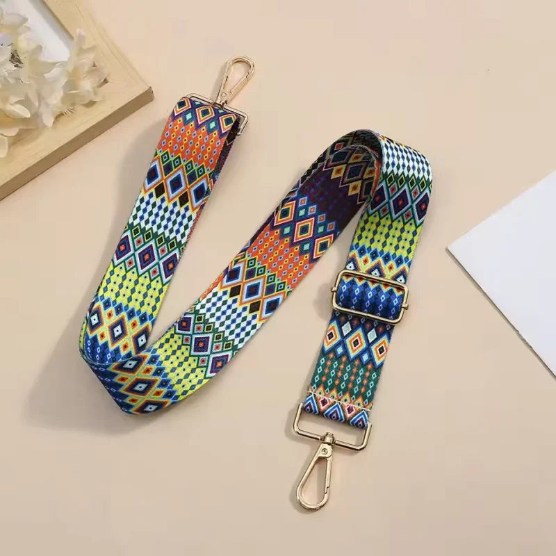 A colorful patterned nylon crossbody bag strap with gold hardware is displayed on a light background.