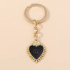 Gold chain keychain featuring a black heart pendant with a sun eye detail.