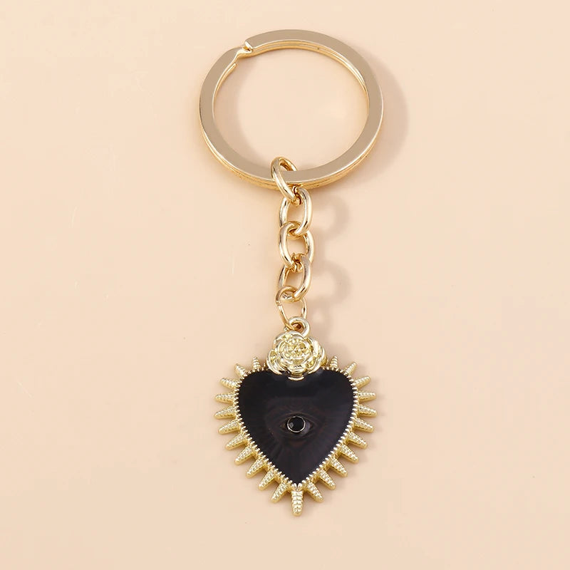 Gold chain keychain featuring a black heart pendant with a sun eye detail.