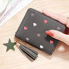 A dark gray PU leather compact wallet with a zipper closure decorated with small pink and gray heart shapes and attached to a