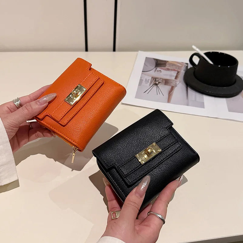 A hand holds an orange leather multi-slot card holder next to a black cup on a white table.