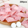 Une pile de 200 serviettes faciales en coton compressé et réutilisables roses sont exposées sur une planche en bois.