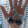Silver crystal fruit charm keychain featuring two dark, speckled apples.